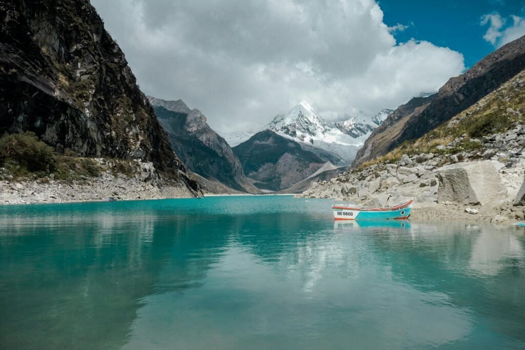 Stunning turquoise lake surrounded by mountains in Huaraz, Peru on a crisp day with a lonely boat.