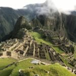 Stunning aerial view of Machu Picchu with lush mountains and clouds in the background.